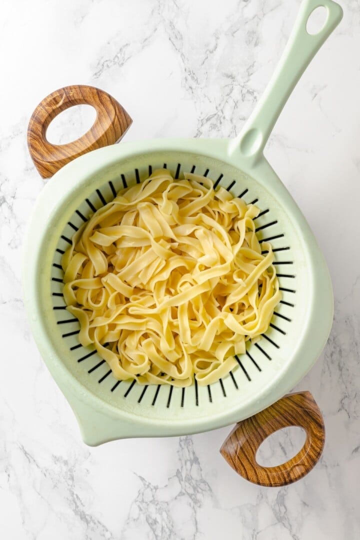 This vegan “chicken” Alfredo recipe is made with budget-friendly soy curls to replace the meat. It’s rich, garlicky and creamy. So good! Fettuccine in colander.