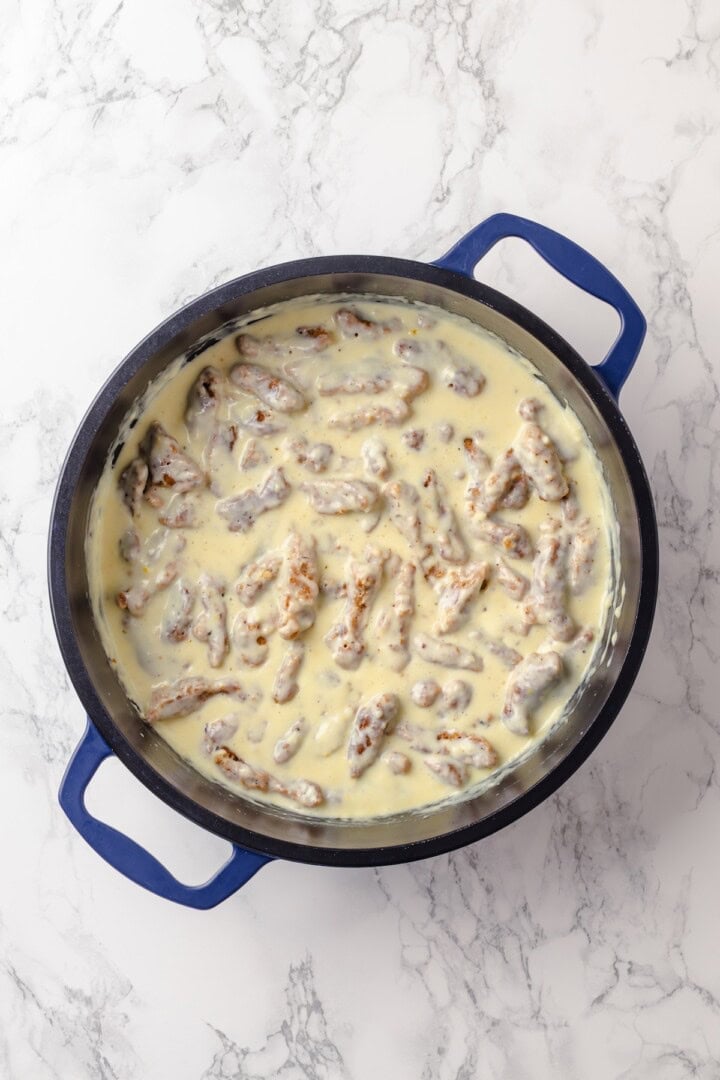This vegan “chicken” Alfredo recipe is made with budget-friendly soy curls to replace the meat. It’s rich, garlicky and creamy. So good! Cream sauce and soy curls in pan.