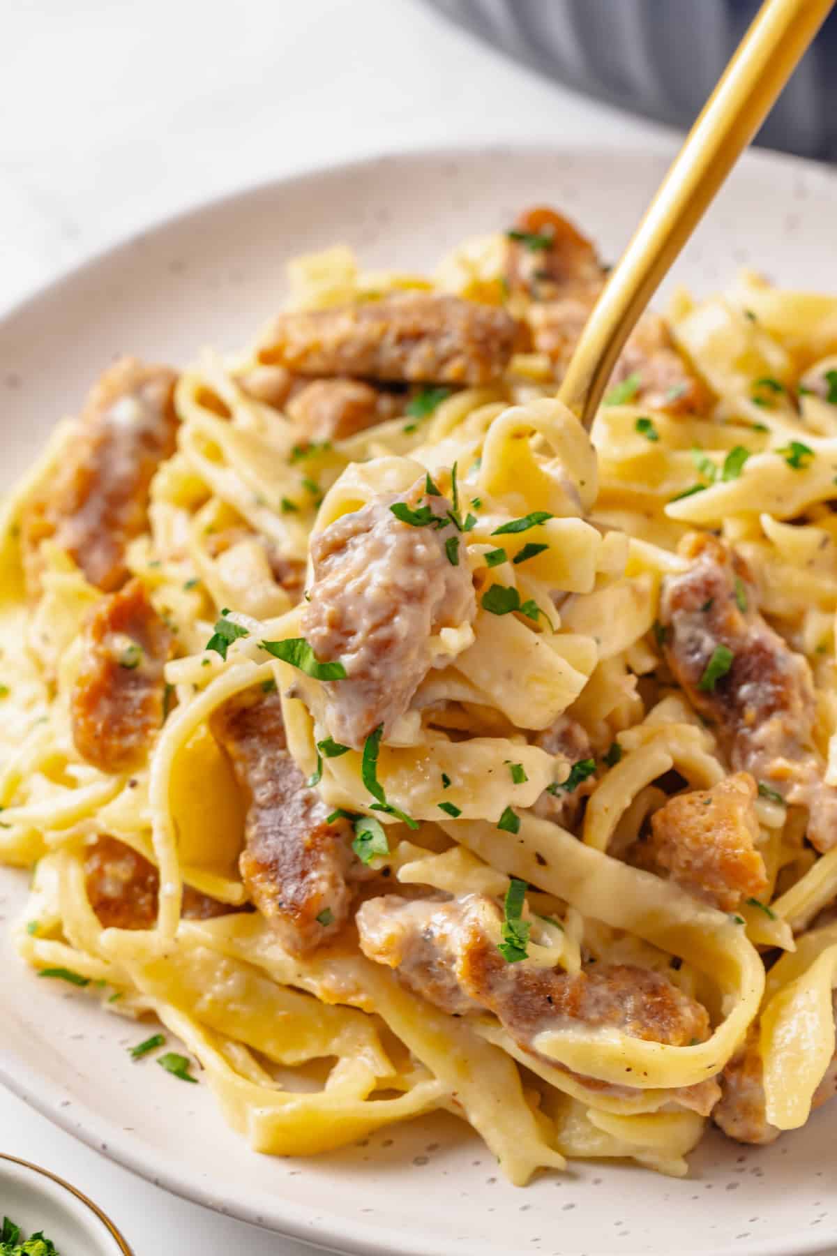 This vegan “chicken” Alfredo recipe is made with budget-friendly soy curls to replace the meat. It’s rich, garlicky and creamy. So good! Forkful of soy curl chicken alfredo on plate.