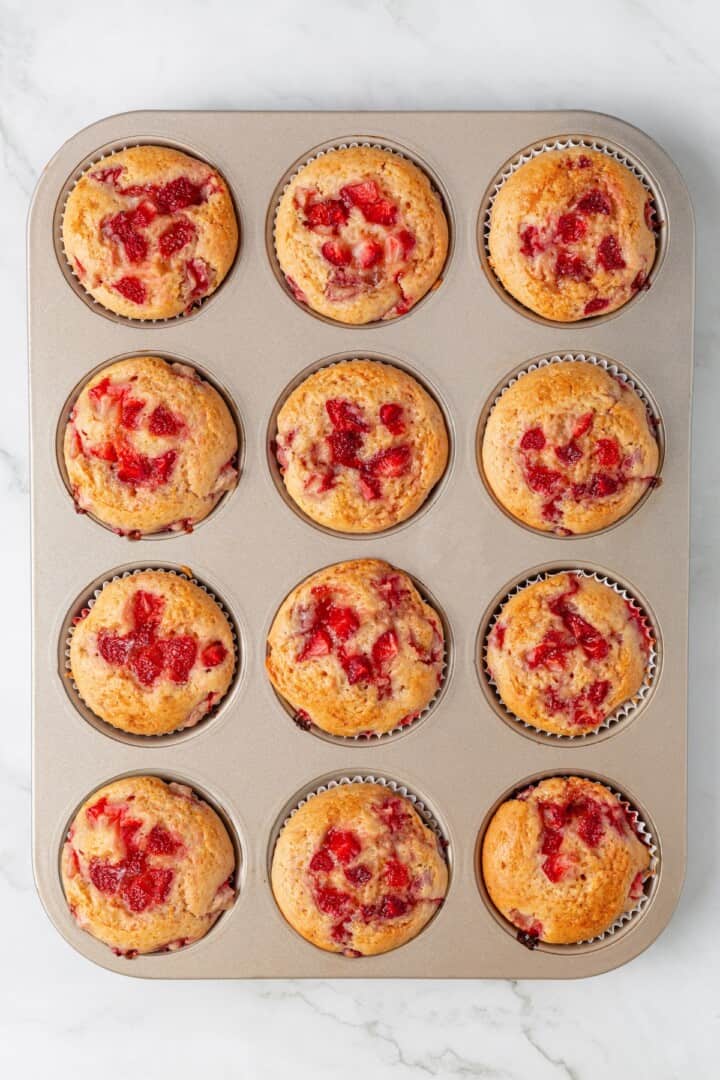 These Vegan Strawberry Muffins are top-notch. Tender, fluffy, and loaded with fresh fruit, they're the perfect way to start the day. Strawberry muffins resting in a muffin tin.