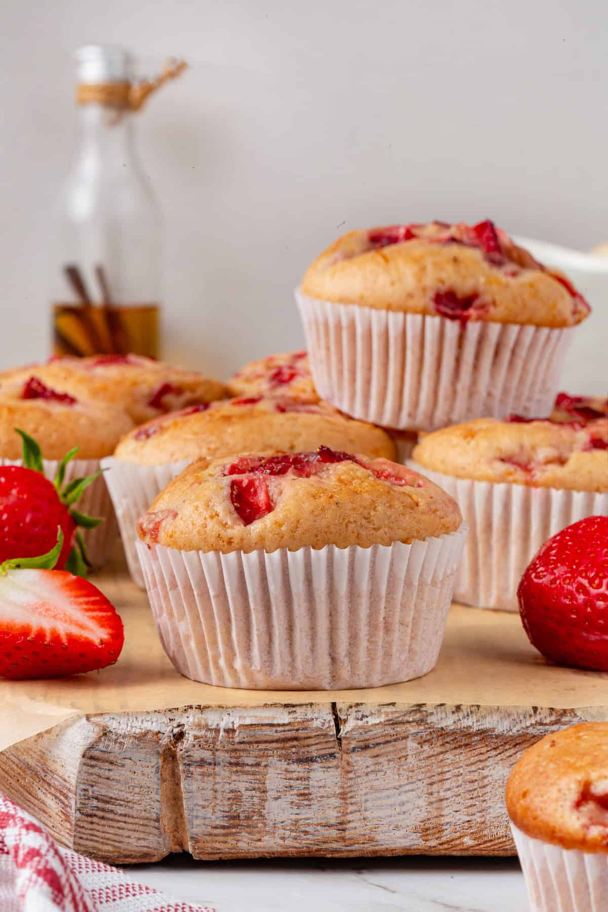 These Vegan Strawberry Muffins are top-notch. Tender, fluffy, and loaded with fresh fruit, they're the perfect way to start the day. Side-view of vegan strawberry muffins on a wooden surface.