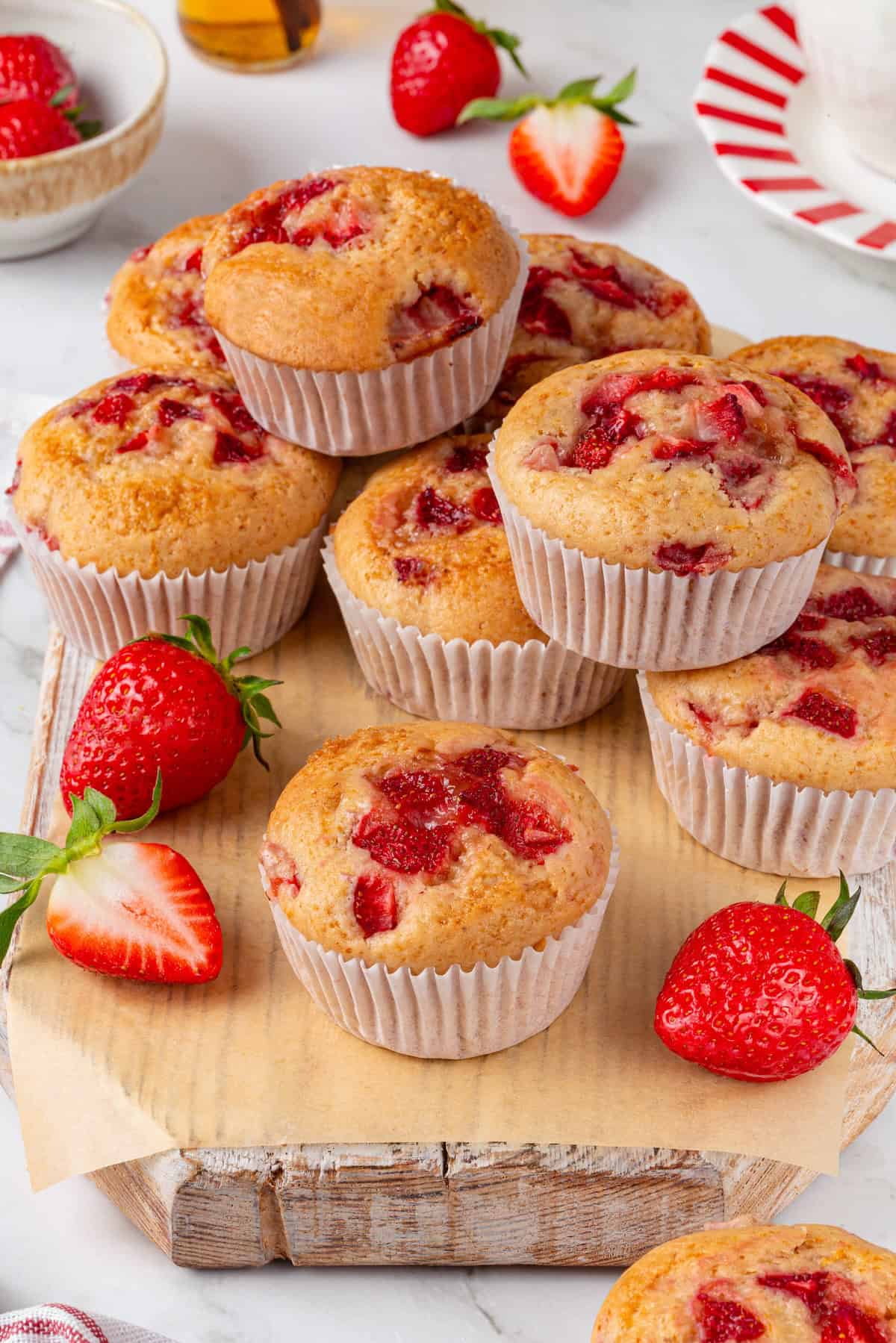 These Vegan Strawberry Muffins are top-notch. Tender, fluffy, and loaded with fresh fruit, they're the perfect way to start the day. Overhead image of strawberry muffins piled on a wooden surface.