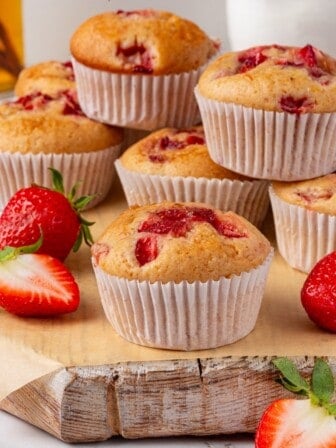 Strawberry muffins piled on a wooden surface.