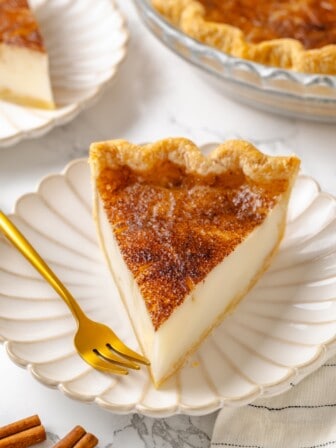 Slice of sugar cream pie on plate with gold fork.