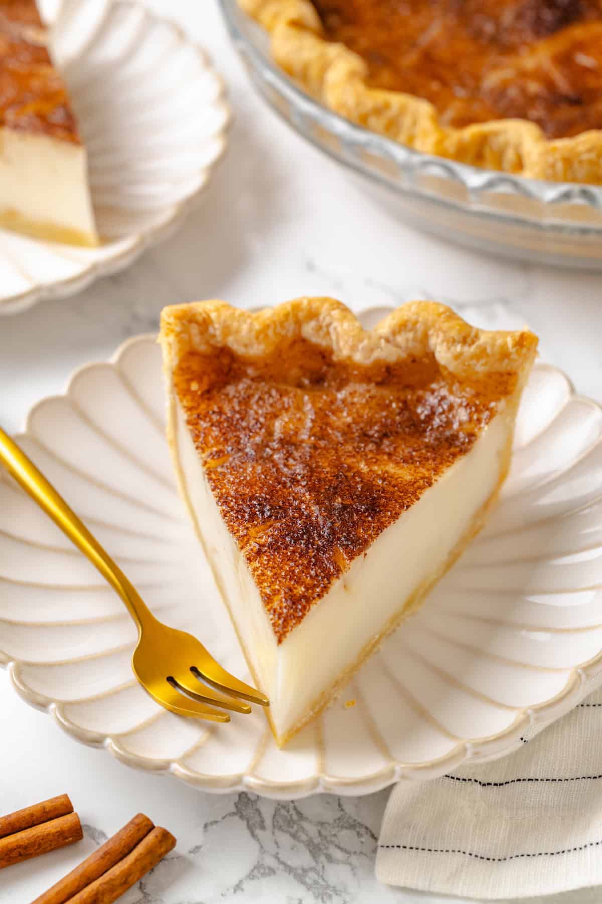 Slice of sugar cream pie on plate with gold fork.