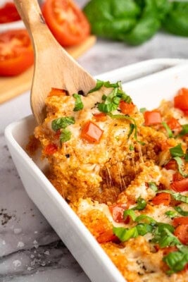 A wooden spatula diving into quinoa casserole.