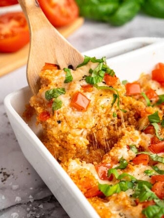 A wooden spatula diving into quinoa casserole.