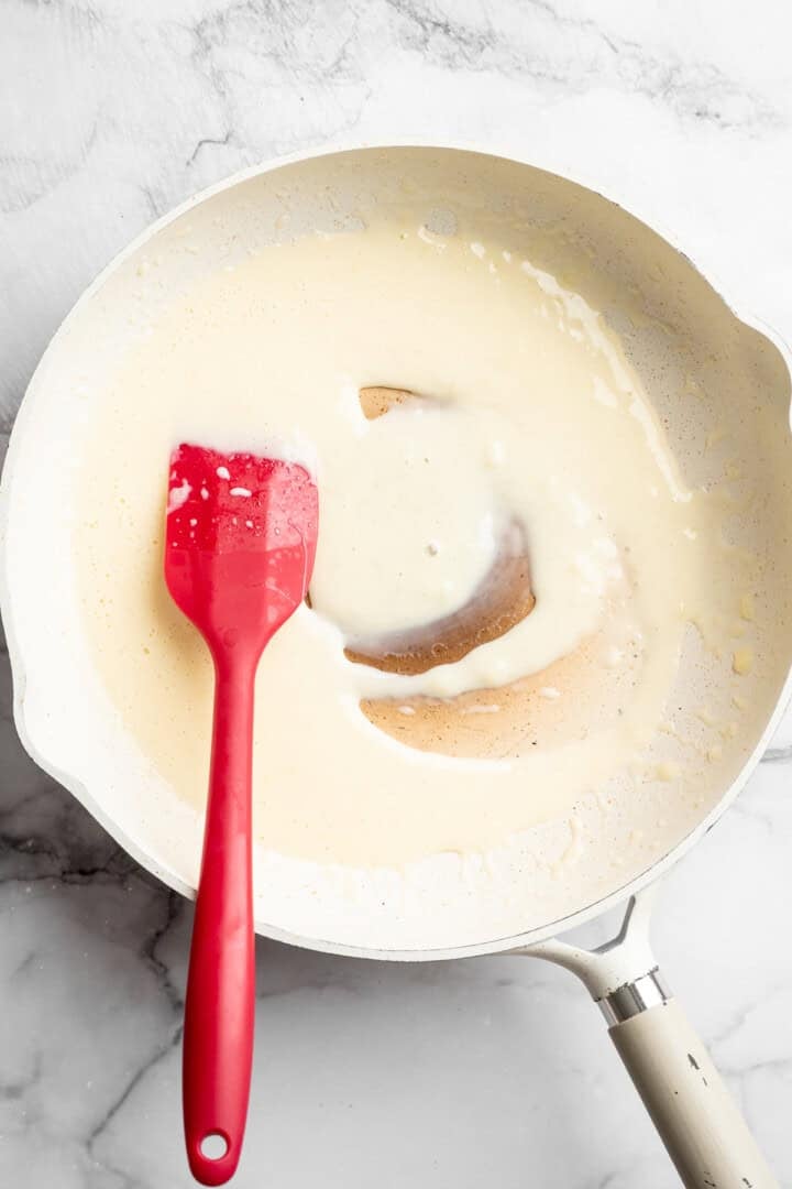 Heating milk and vegan mozzarella in a skillet.