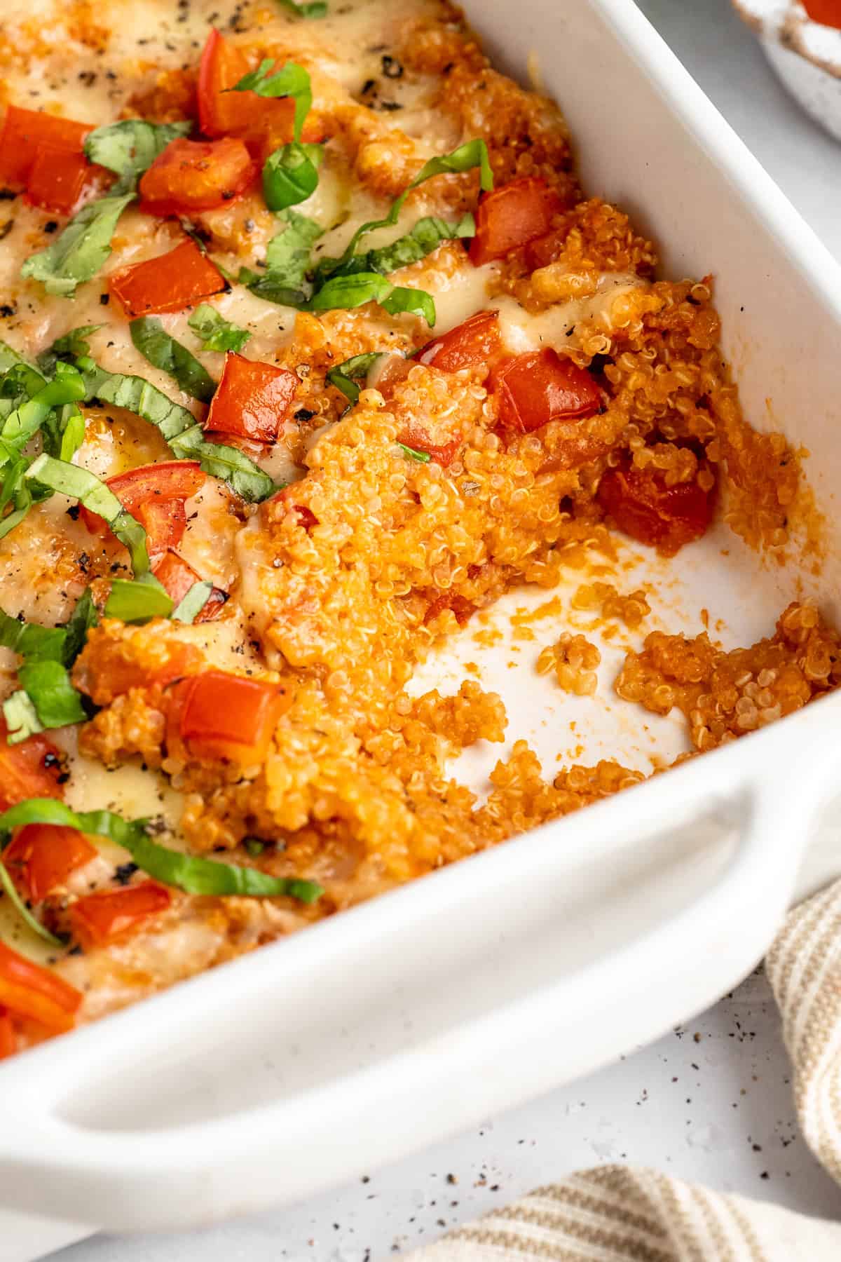 Cheesy quinoa casserole with a serving removed from the corner of the baking dish.