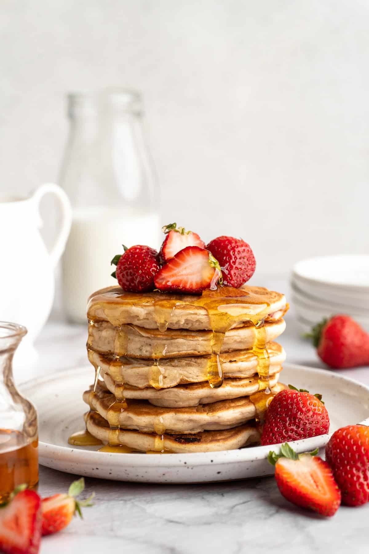 These strawberry pancakes are incredibly fluffy and jam-packed with fresh strawberries. Plus, they're gluten-free and vegan! A stack of gluten-free strawberry pancakes topped with fresh strawberries and maple syrup.