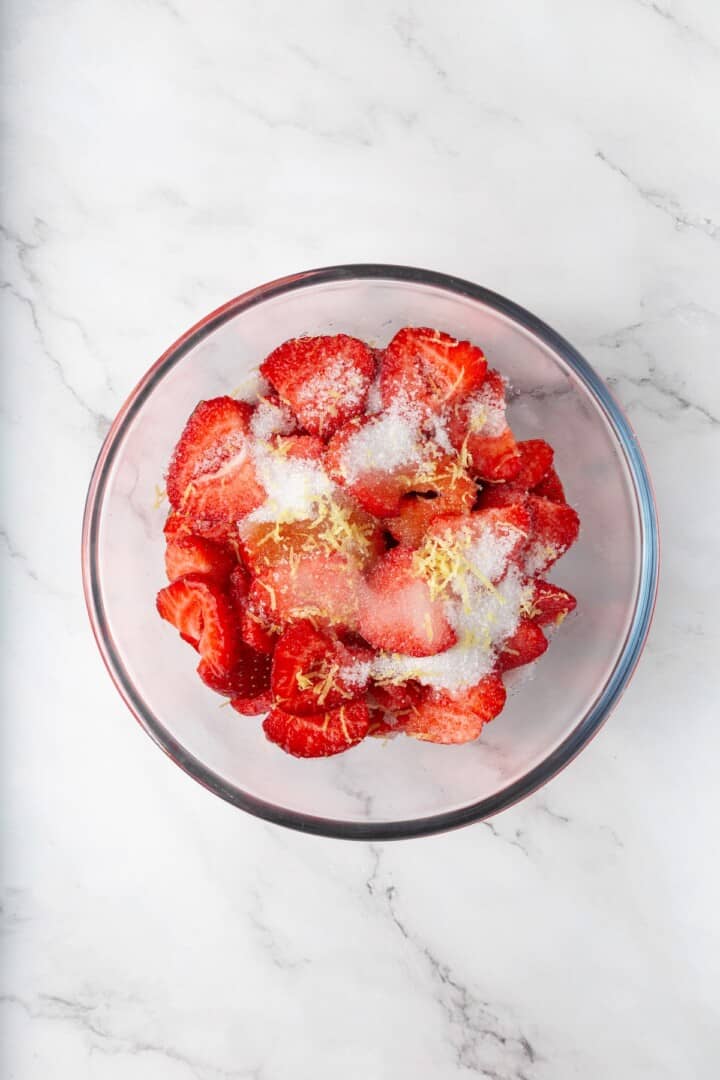 These beautifully simple macerated strawberries are so sweet and syrupy. They're a perfect addition to the breakfast OR dessert table. Sliced strawberries in a bowl topped with sugar, lemon juice, lemon zest, vanilla, and a little salt.
