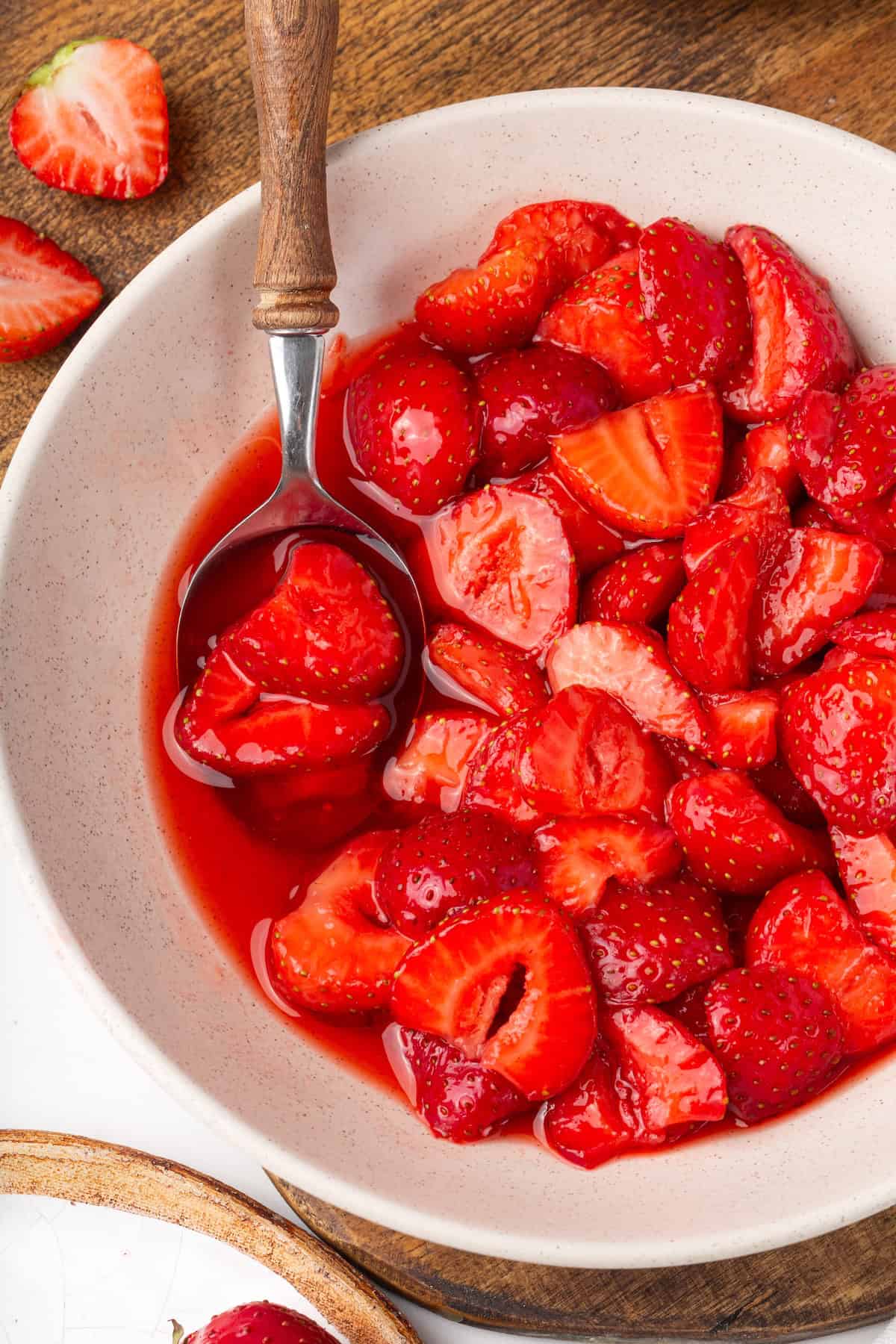 These beautifully simple macerated strawberries are so sweet and syrupy. They're a perfect addition to the breakfast OR dessert table. A bowl of macerated strawberries with a spoon in it.