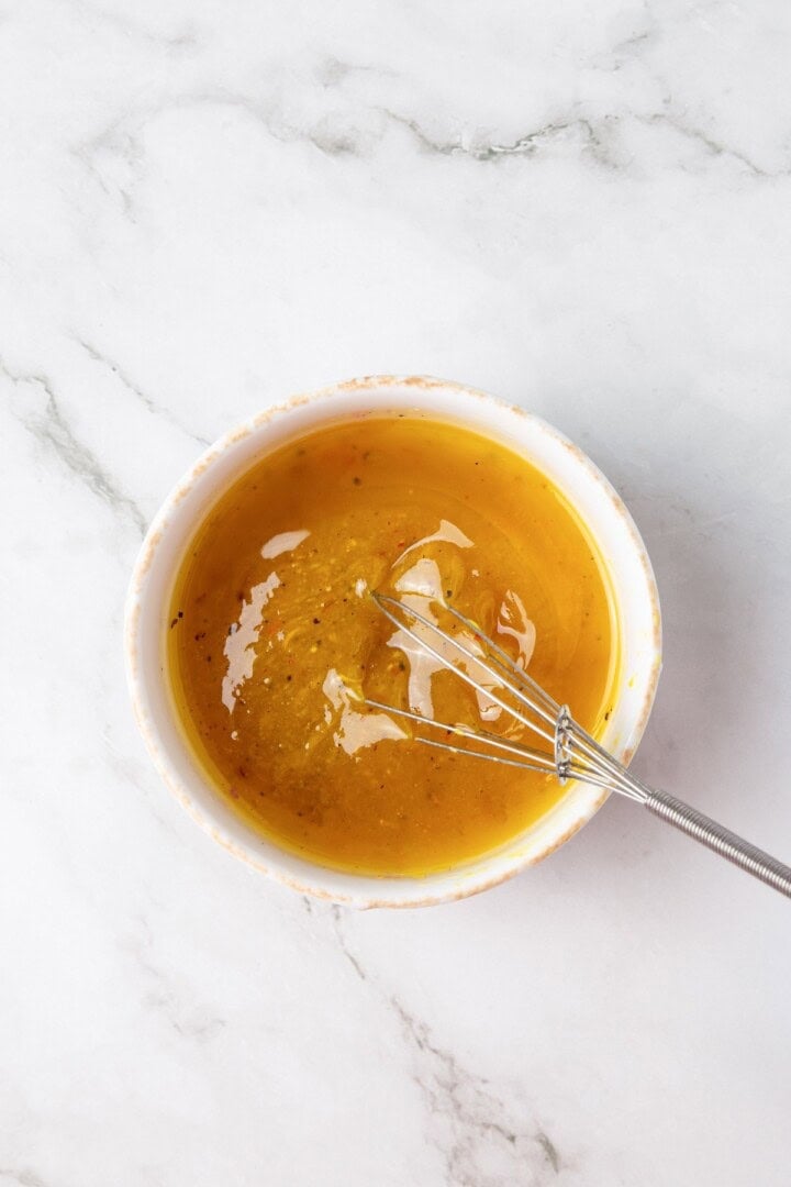 These easy marinated beans are soaked in a bright lemon-Dijon marinade with fresh herbs and aromatics. The perfect summer side. Whisking together the marinade for marinated white beans.