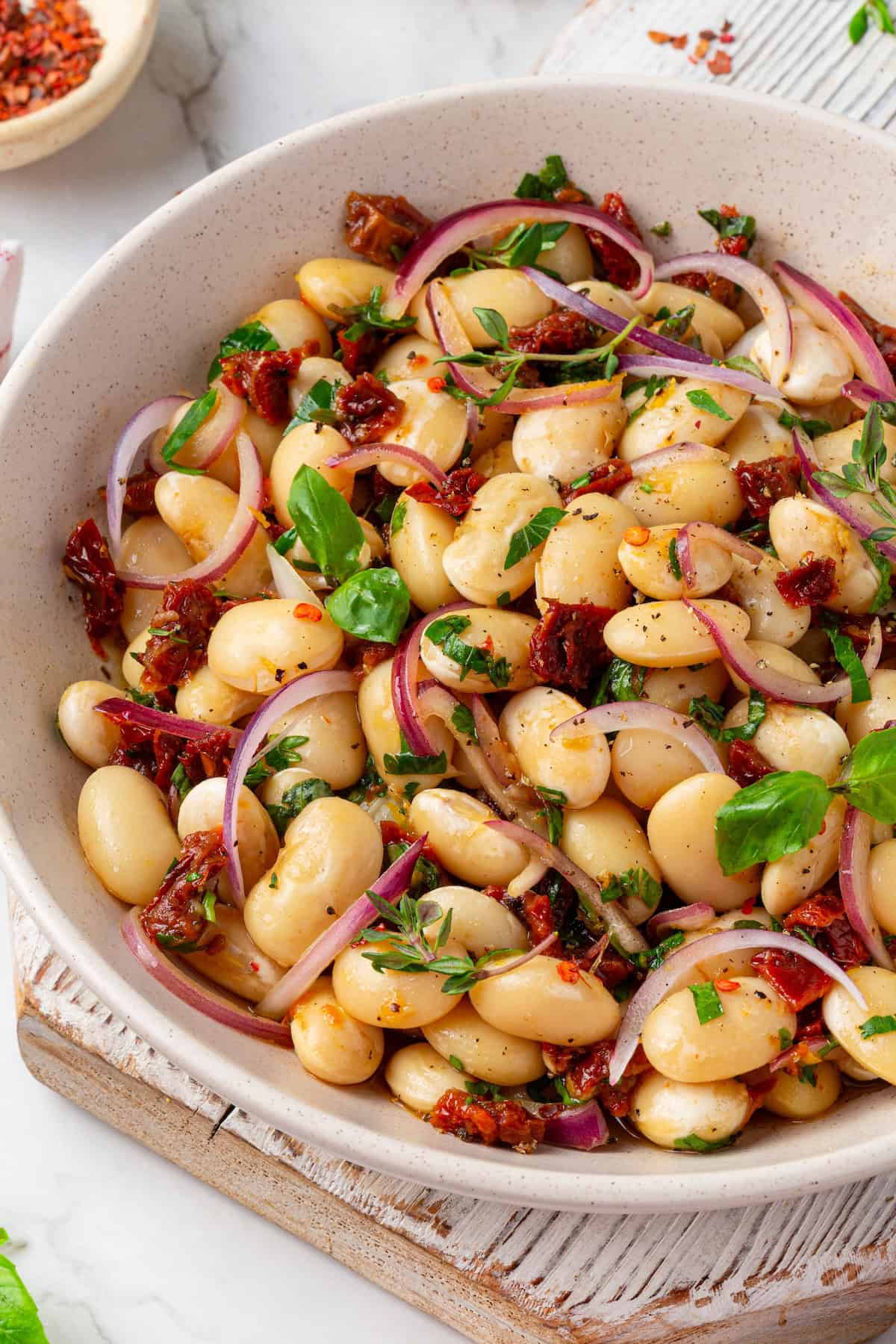 These easy marinated beans are soaked in a bright lemon-Dijon marinade with fresh herbs and aromatics. The perfect summer side. Marinated white beans in a serving bowl.