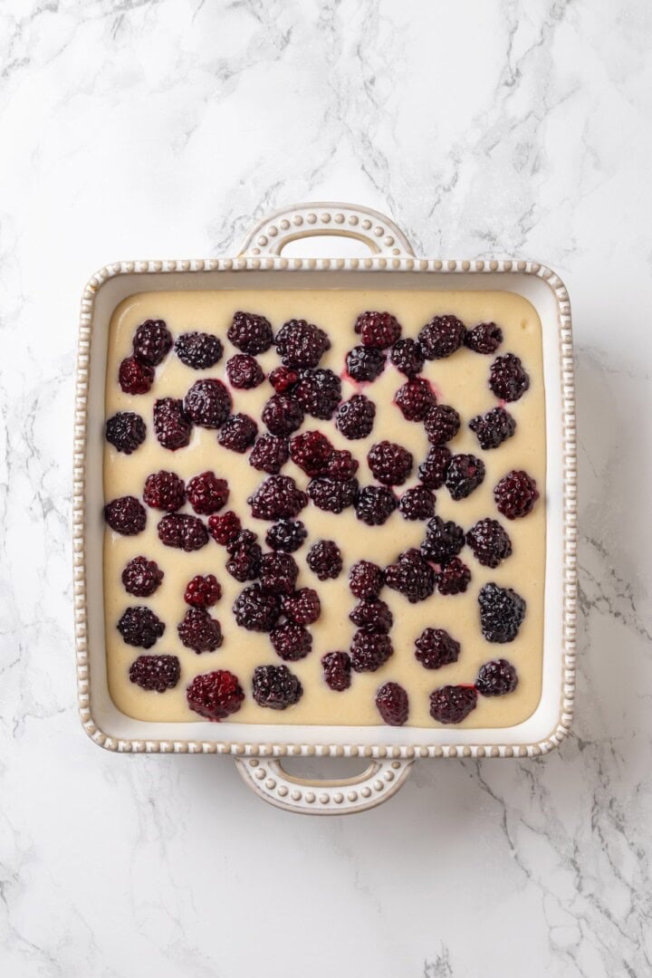 This blackberry cobbler, with its fluffy batter topping and juicy, bubbling blackberries is a summer staple you don't want to miss. Cobbler batter topped with blackberries, ready to go in the oven.
