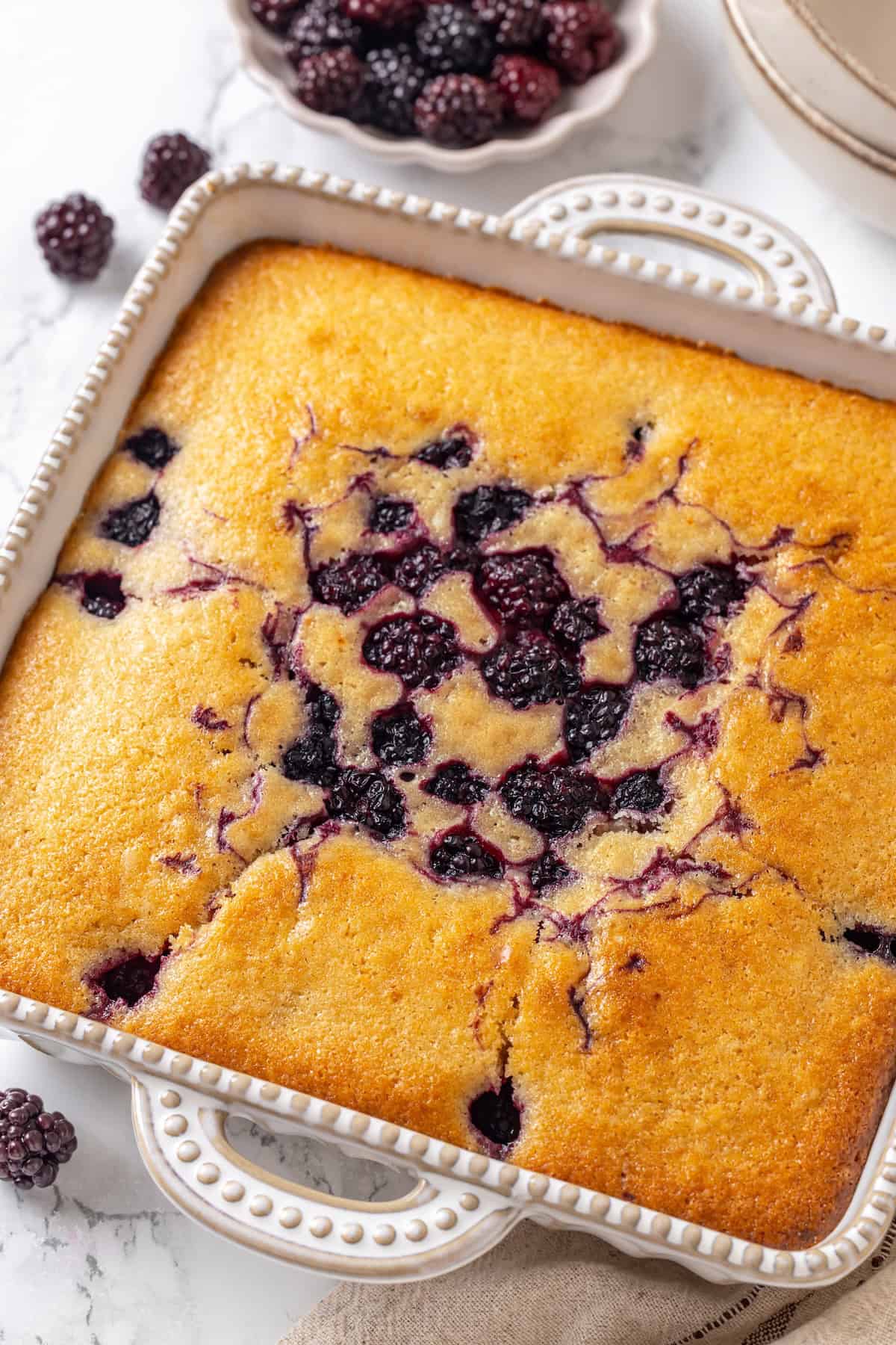 This blackberry cobbler, with its fluffy batter topping and juicy, bubbling blackberries is a summer staple you don't want to miss. Blackberry cobbler in a baking pan.