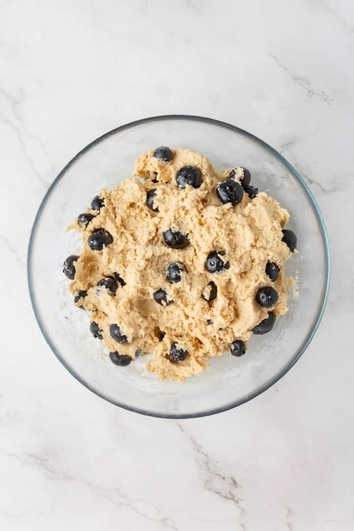Loaded with jammy pockets of fresh berries and topped with a sweet lemon glaze, these vegan blueberry cookies are a summer must. Vegan blueberry lemon cookie dough in a bowl.