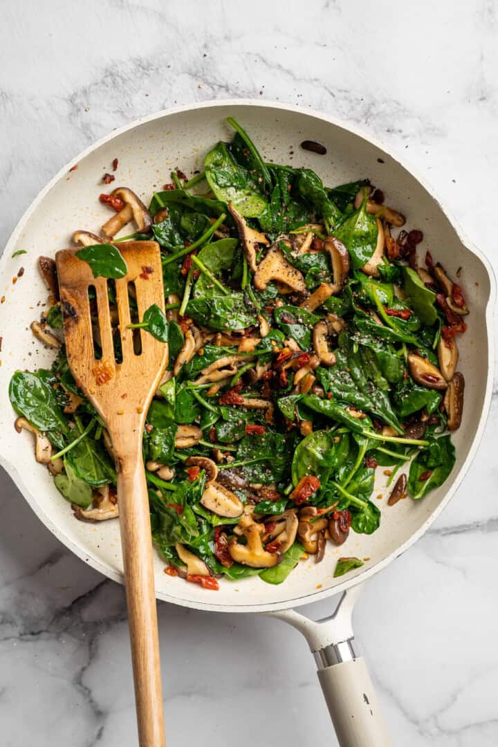 Saucy and loaded with veggies, this vegan cheesy pasta bake is topped with bubbly, melty vegan cheese. It's the ideal weeknight comfort food. Wilting spinach in a skillet with sautéed mushrooms, sun-dried tomatoes, and garlic.