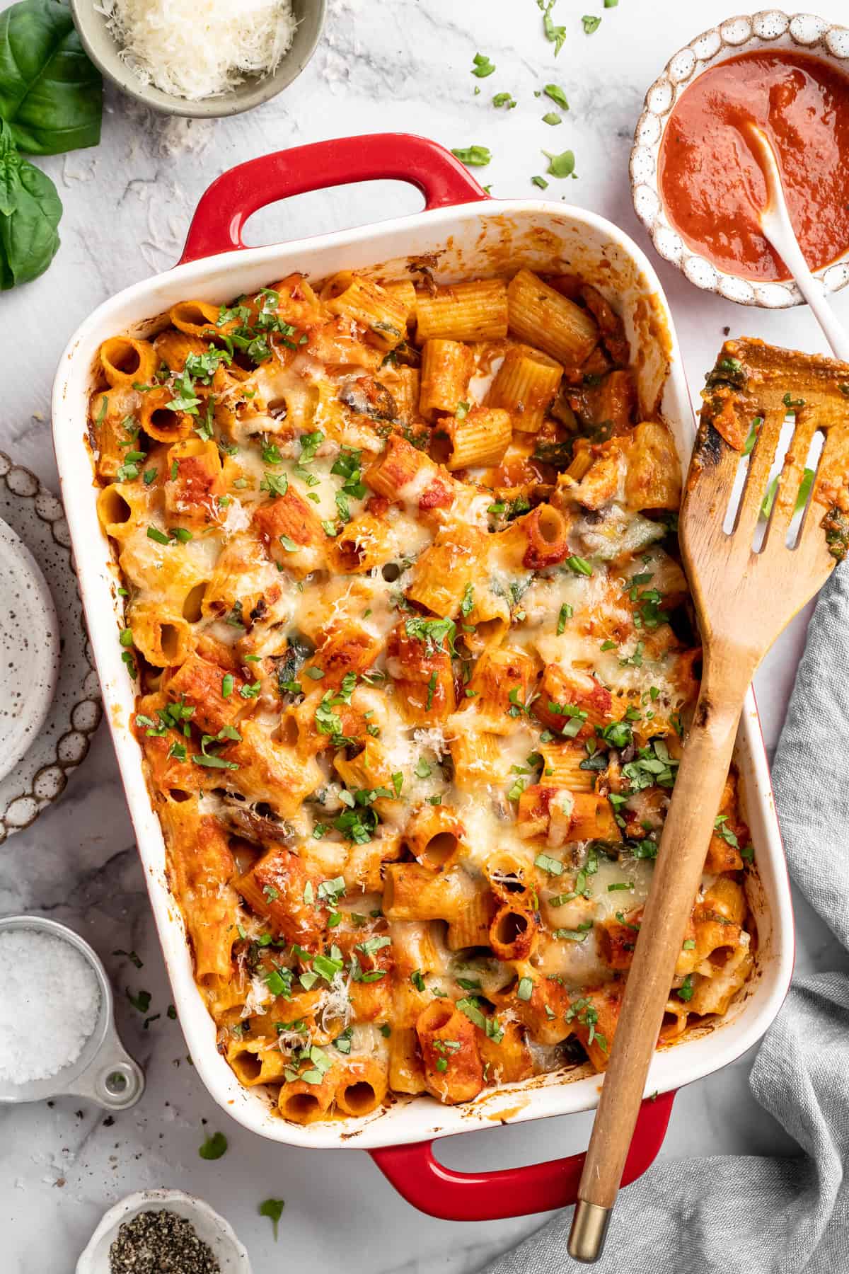 Saucy and loaded with veggies, this vegan cheesy pasta bake is topped with bubbly, melty vegan cheese. It's the ideal weeknight comfort food. Cheese vegan pasta bake with a spatula that's recently scooped out a serving.