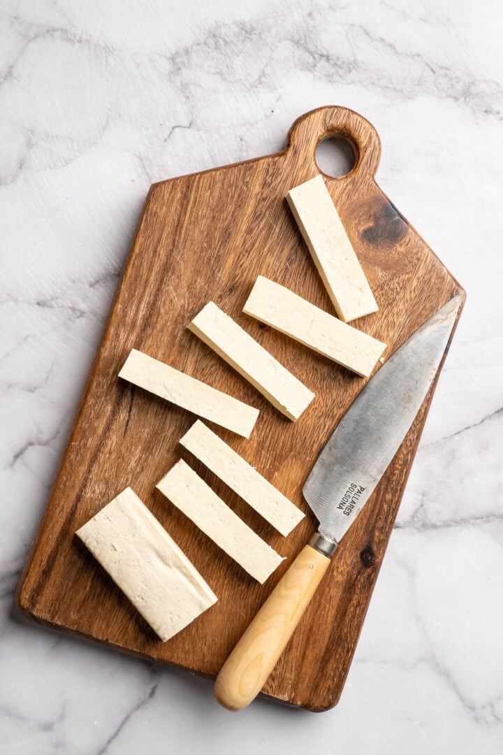 This tofu salad, topped with Cajun fried tofu and creamy, tangy-sweet dressing, is just as good as TGI Friday's version. And it's vegan! Cutting pressed tofu into strips.