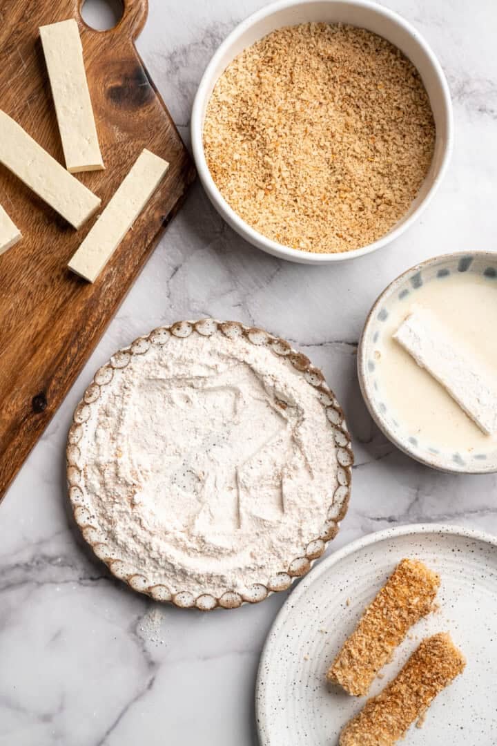 This tofu salad, topped with Cajun fried tofu and creamy, tangy-sweet dressing, is just as good as TGI Friday's version. And it's vegan! Dipping a flour-coated tofu strip in vegan buttermilk.