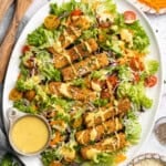 Overhead image of Cajun fried tofu salad on a plate with extra dressing on the side.