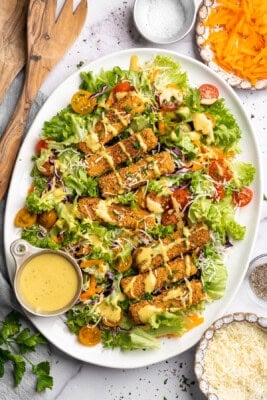Overhead image of Cajun fried tofu salad on a plate with extra dressing on the side.