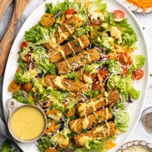 Overhead image of Cajun fried tofu salad on a plate with extra dressing on the side.