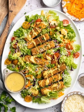 Overhead image of Cajun fried tofu salad on a plate with extra dressing on the side.