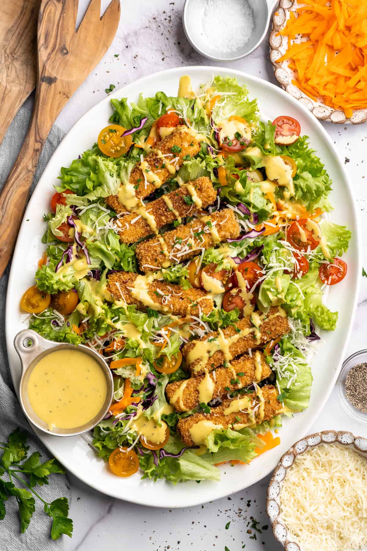 This tofu salad, topped with Cajun fried tofu and creamy, tangy-sweet dressing, is just as good as TGI Friday's version. And it's vegan! Overhead image of Cajun fried tofu salad on a plate with extra dressing on the side.