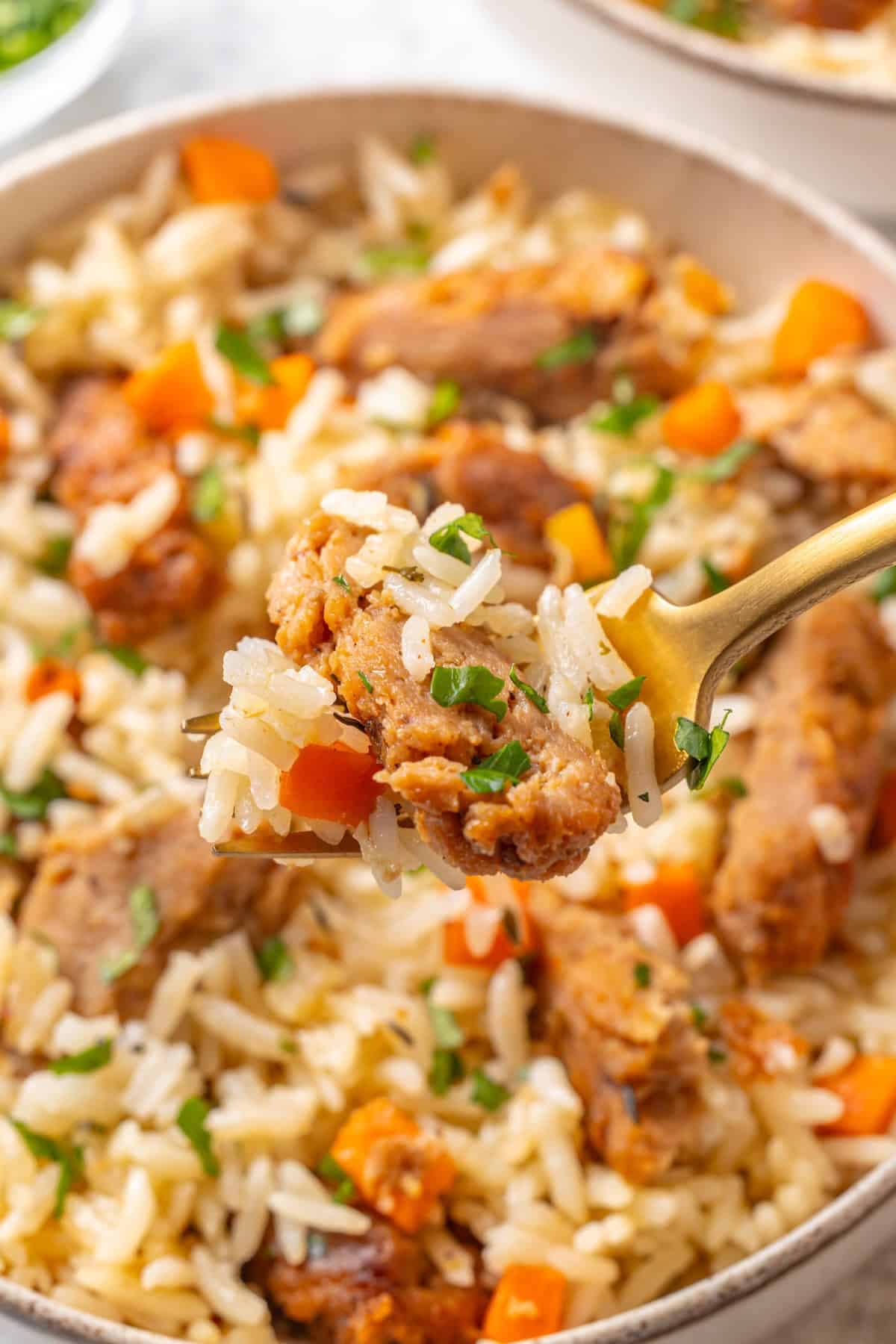 This vegan "chicken" and rice delivers all the cozy, savoury goodness of the meat-eater's version, no chicken required. A fork holding a bite of vegan "chicken" and rice up to the camera.