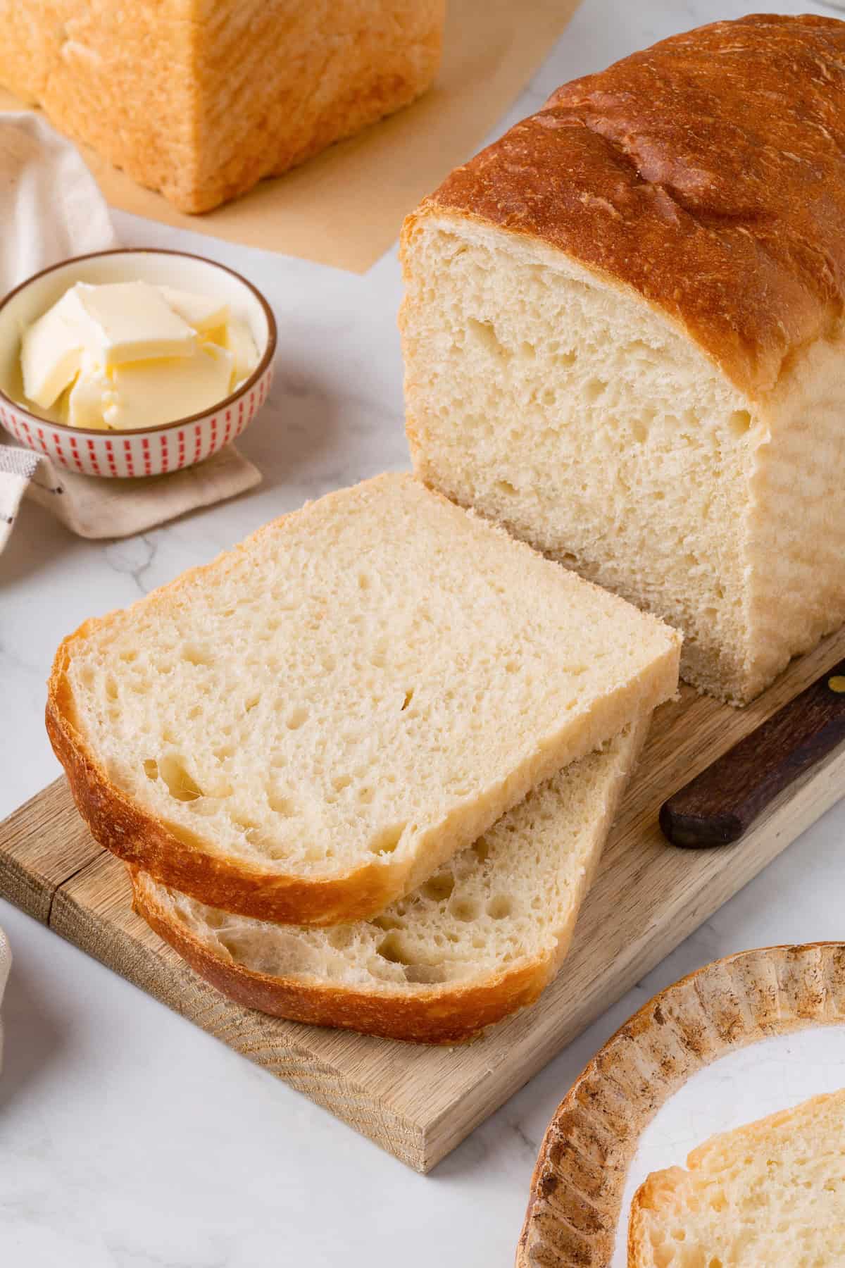This easy vegan Sandwich Bread Recipe is a home baker's dream. Soft and pillowy with a subtle richness, it's a major upgrade to any sandwich. A loaf of sandwich bread with two slices cut from it.