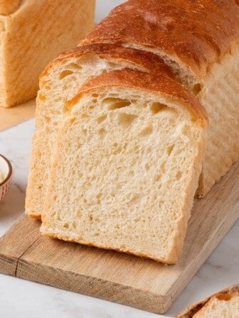 A loaf of sandwich bread with two slices leaning against it.