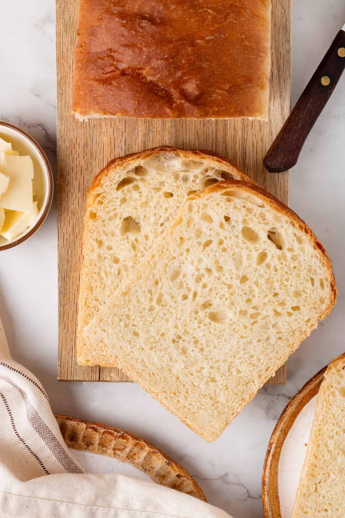 This easy vegan Sandwich Bread Recipe is a home baker's dream. Soft and pillowy with a subtle richness, it's a major upgrade to any sandwich. Overhead image of slices of vegan sandwich bread on a cutting board.