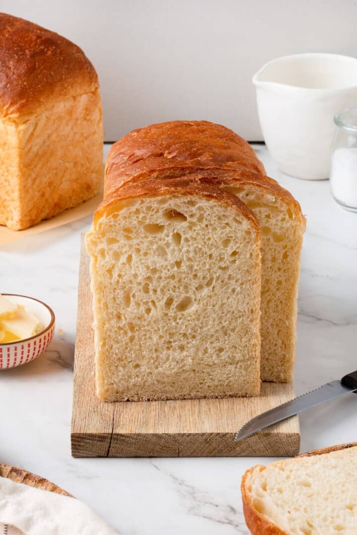 This easy vegan Sandwich Bread Recipe is a home baker's dream. Soft and pillowy with a subtle richness, it's a major upgrade to any sandwich. Side-view of a loaf os sandwich bread, sliced to reveal the tender crumb.