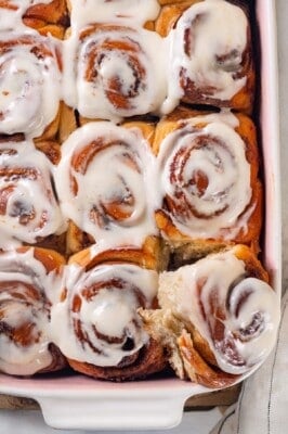 A pan of vegan sourdough cinnamon rolls. The corner roll is pulled out slightly.