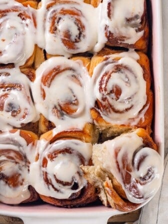 A pan of vegan sourdough cinnamon rolls. The corner roll is pulled out slightly.