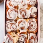 A pan of vegan sourdough cinnamon rolls. The left corner roll is pulled out slightly.