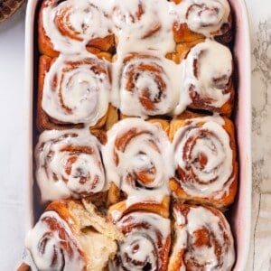 A pan of vegan sourdough cinnamon rolls. The left corner roll is pulled out slightly.
