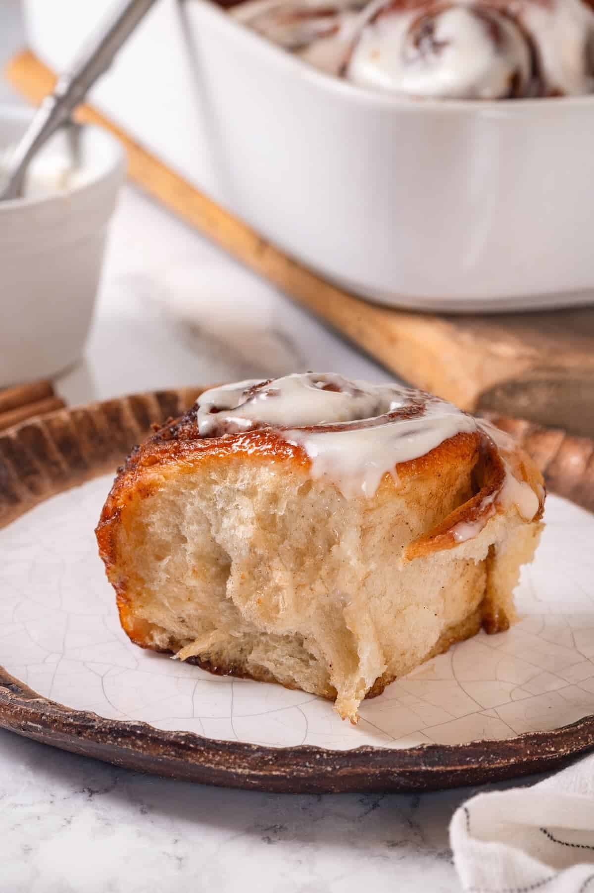 These vegan sourdough cinnamon rolls are impossibly soft, packed with cinnamon sugar filling, and topped with a smooth cream cheese glaze. A sourdough cinnamon bun on a plate.