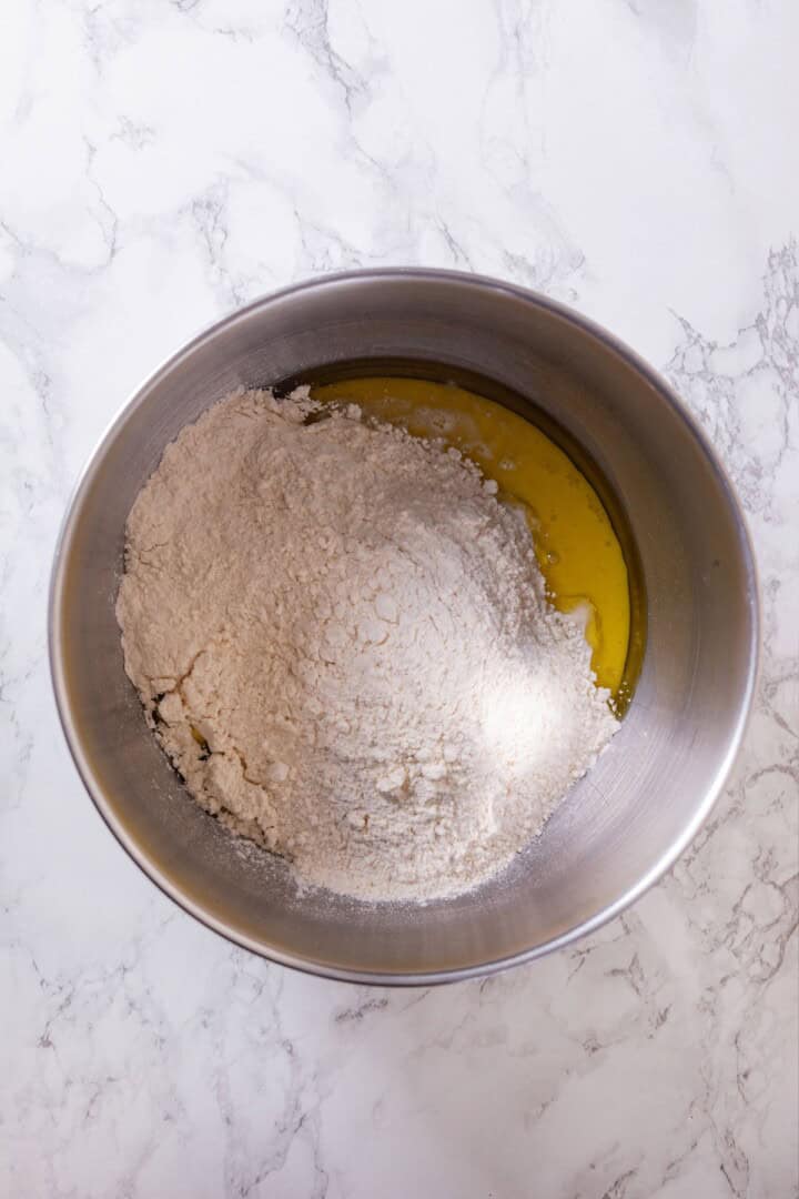 These vegan sourdough cinnamon rolls are impossibly soft, packed with cinnamon sugar filling, and topped with a smooth cream cheese glaze. Plant milk, coconut cream, active sourdough starter, olive oil, and flour in a bowl.