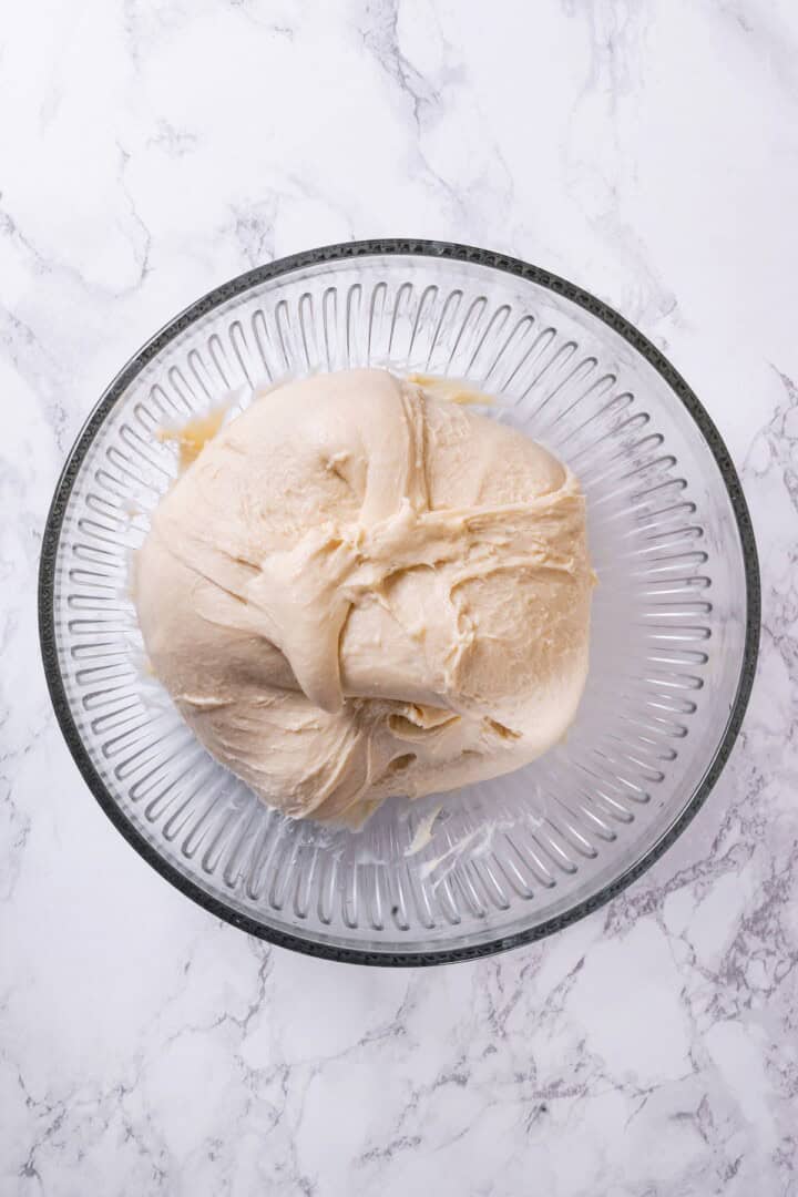 These vegan sourdough cinnamon rolls are impossibly soft, packed with cinnamon sugar filling, and topped with a smooth cream cheese glaze. Stretching each corner of dough toward the center.