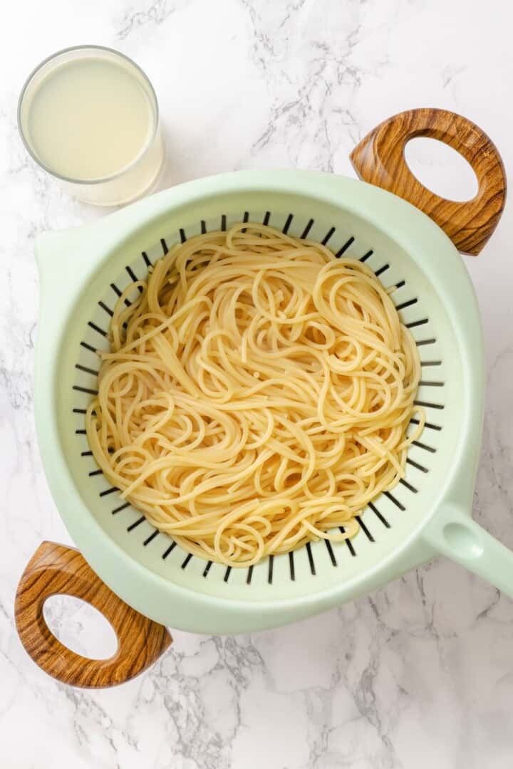 This easy aglio e olio features al dente spaghetti coated in a velvety garlic-infused sauce with a touch of heat from red pepper flakes. Drained spaghetti in a colander.