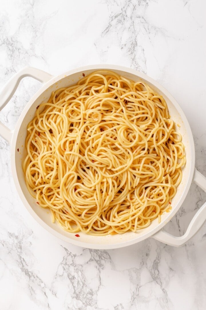 This easy aglio e olio features al dente spaghetti coated in a velvety garlic-infused sauce with a touch of heat from red pepper flakes. Tossing spaghetti in aglio e olio sauce.