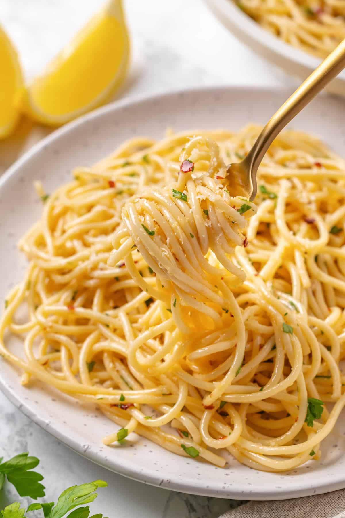 This easy aglio e olio features al dente spaghetti coated in a velvety garlic-infused sauce with a touch of heat from red pepper flakes. A fork twirling a bite of spaghetti aglio e olio.