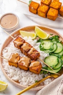 Tofu satay served with jasmine rice, cucumber, lime, cilantro, and Thai peanut sauce.