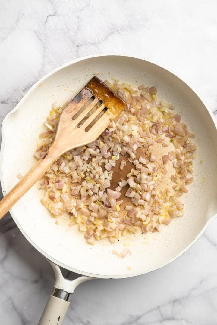 These 30-minute smoky white beans in tomato sauce are made with liquid smoke and plenty of garlic. They're amazing on toast for breakfast! Sautéing chopped onion and minced garlic in olive oil.