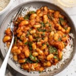 Overhead image of smoky white beans in tomato sauce served over white rice.