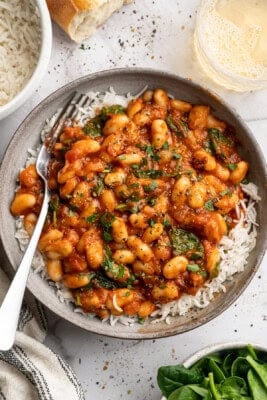 Overhead image of smoky white beans in tomato sauce served over white rice.