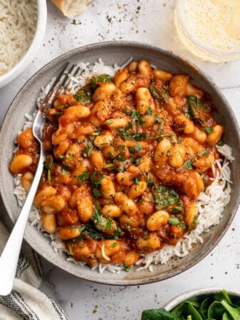 Overhead image of smoky white beans in tomato sauce served over white rice.